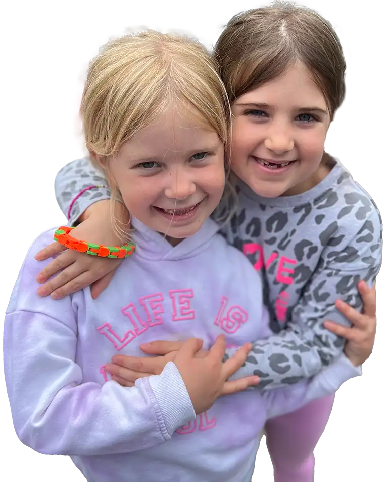 Two little girls with their arms around each other, wearing hoodies