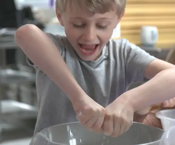 Little boy rubbing fat into flour in a mixing bowl